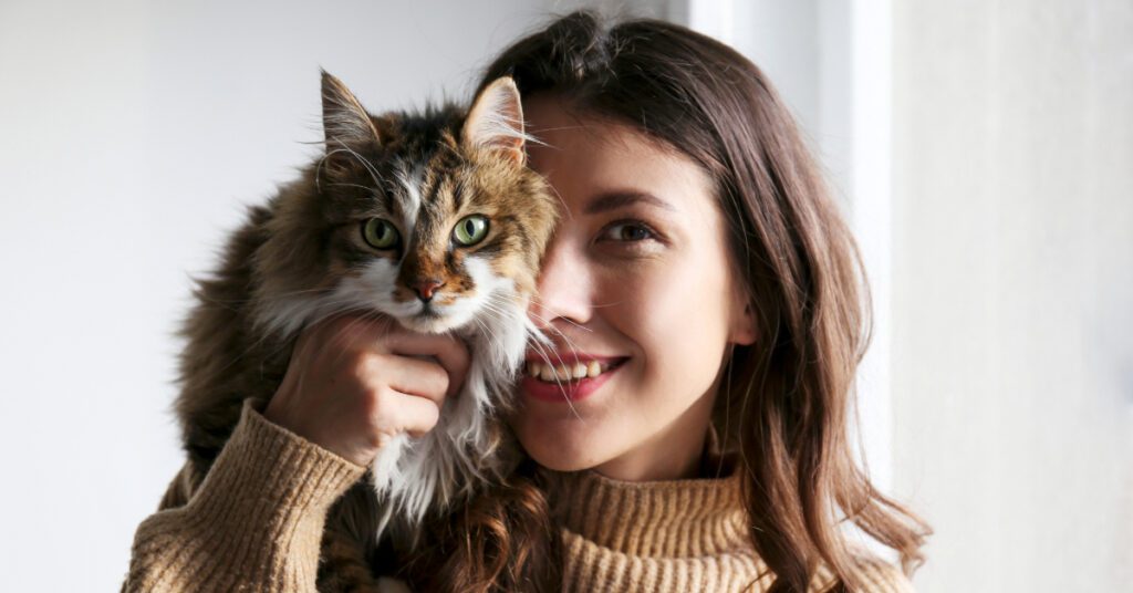 young female cat owner holding her cat close to her face
